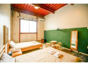 Cette chambre comprend 2 lits et un mur vert. dans l'établissement fan! -ABURATSU- Sports Bar & HOSTEL - Vacation STAY 78433v, à Nichinan