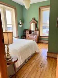 a bedroom with a bed and a dresser and two windows at The Woodbridge House in Kingsville