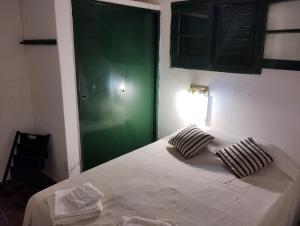 1 dormitorio con cama blanca y puerta verde en GREEN HOME en Córdoba