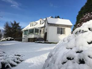 una casa blanca con nieve en la entrada en Craigievern Cottage, en Drymen