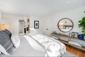 1 dormitorio blanco con 1 cama blanca grande y espejo en Wine Country Creekside Retreat With Hot Tub, en Glen Ellen