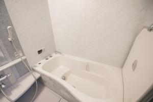 una vasca bianca in bagno con specchio di Tokai Ryokan Ichigokan - Vacation STAY 29187v ad Atami