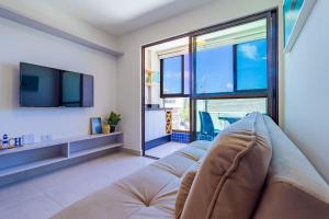 a living room with a couch and a large window at Porto Blue #303 - Apartamento por Carpediem in Porto De Galinhas