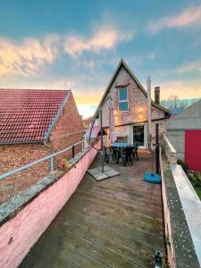 una casa con terraza de madera junto a un edificio en Das Haus am Bach - Schöne große moderne Wohnung mit Terrasse, en Osthofen