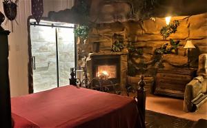 a stone room with a fireplace and a table and a bed at Auberge Aux Nuits de Rêve in Sainte-Agathe-des-Monts