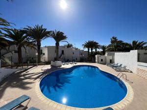a large swimming pool with chairs and palm trees at Casita Vito Fuerteventura in Costa Calma