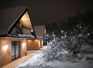 ein Haus ist nachts mit Schnee bedeckt in der Unterkunft Domki przy skwerku in Zakopane