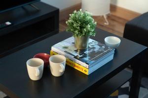 a table with three cups and a vase on top of books at 2 bedroom flat near London ExCel in London