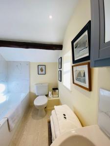 a bathroom with a toilet and a bath tub at Vine Cottage in Chipping Campden