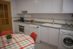 a kitchen with a table and a sink and a washing machine at AP Plaza la Hispanidad in Cuenca
