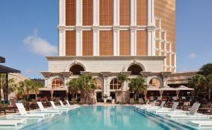 a pool in front of a building with lounge chairs at Horseshoe Bossier City, A Caesars Destination in Bossier City