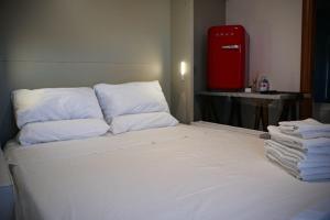 a bed with white pillows and a red refrigerator at Il grifo in Licata