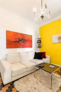 a living room with a white couch and a yellow wall at Linda Leblon Homestay - 3 min to the beach in Rio de Janeiro