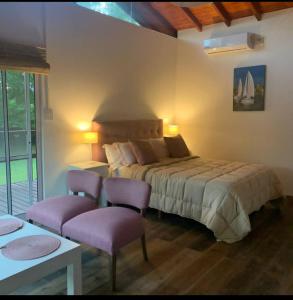 a bedroom with a bed and two purple chairs at Cabañas Burdeos in Tigre