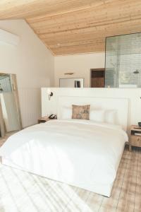 a large white bed in a bedroom with a wooden ceiling at Calamigos Guest Ranch and Beach Club in Malibu