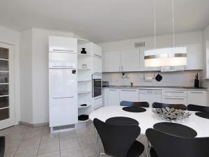6 person holiday home in Bogense في بوجنسي: مطبخ أبيض مع طاولة وكراسي سوداء