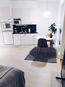 a white kitchen with a table and a chair at New Studio Mint near Airport in Vantaa