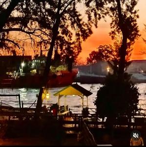 een zonsondergang boven een waterlichaam met bomen en tafels bij Cabañas Burdeos in Tigre