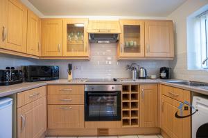 a kitchen with wooden cabinets and a stove top oven at Franklin House 2 bed, king bed, parkingx2, workspace, wi-fi, corporates in Hardingstone