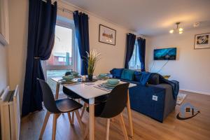 een woonkamer met een tafel en een blauwe bank bij Franklin House 2 bed, king bed, parkingx2, workspace, wi-fi, corporates in Hardingstone