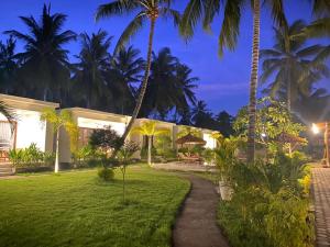 une villa avec une pelouse et des palmiers la nuit dans l'établissement The Kebon Lombok, à Kuta Lombok