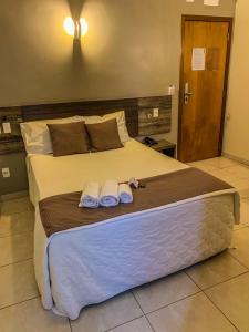 1 dormitorio con 1 cama grande y toallas. en Hotel Piratininga Avenida Amazonas - Rondonópolis, en Rondonópolis