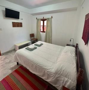 a bedroom with a large white bed and a chair at La Colorada Hostal in Tilcara