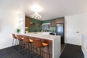 an open kitchen with a bar with stools at TAHUNA LAKEFRONT LUXURY, Central Location in Queenstown