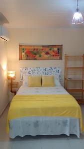 - une chambre avec un grand lit et une couverture jaune dans l'établissement Flores do Riacho, à São Miguel dos Milagres