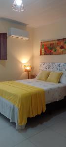 a bedroom with a bed with a yellow blanket on it at Flores do Riacho in São Miguel dos Milagres
