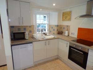 a kitchen with white cabinets and a sink and a microwave at Whinstone Holiday Home in Falkland in Falkland