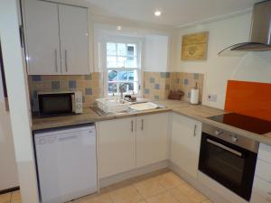 cocina con armarios blancos, fregadero y microondas en Whinstone Holiday Home in Falkland en Falkland