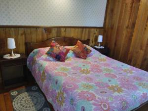 una cama con un edredón colorido y almohadas en ella en Hospedaje Picoyo, en Pucón