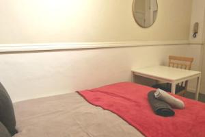 a bedroom with a bed with a red blanket and a table at Private London Kensington studio 2 mins from tube in London