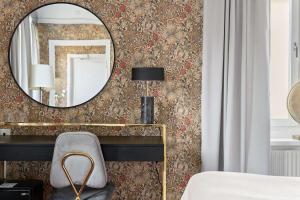 una camera da letto con specchio e scrivania con sedia di Centric Hotel a Norrköping