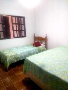 Habitación con 2 camas con sábanas verdes. en Casa próximo a praia de Guarapari, en Guarapari