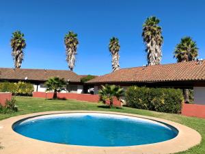 una piscina frente a una casa con palmeras en Cabañas Entre Rios Talca en Talca