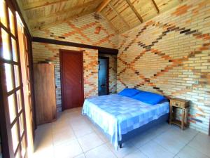 1 dormitorio con cama y pared de ladrillo en MORADA GUARDA PARADISE, en Palhoça