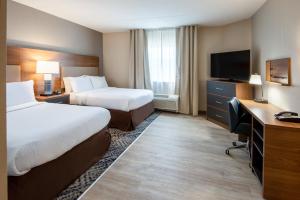 um quarto de hotel com duas camas e uma secretária e uma televisão em Candlewood Suites Manassas, an IHG Hotel em Manassas