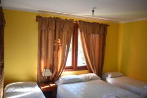 1 dormitorio con 2 camas y ventana en Benitez Hostería en Calilegua