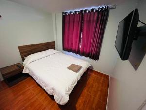 Dormitorio pequeño con cama y TV en Hotel Baños del Inca en Los Baños del Inca