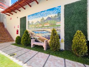 une peinture murale sur le côté d'une maison avec un banc dans l'établissement Hotel Baños del Inca, à Los Baños del Inca