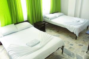 2 camas en una habitación con cortinas verdes en Hotel San Pedro, en Neiva