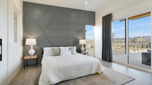 a bedroom with a large bed and a large window at Desert Ridge - Hot Tub, Fire Pit, BBQ, Out Door Shower & Incredi home in Yucca Valley