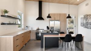 a kitchen with a wooden table and black appliances at Desert Ridge - Hot Tub, Fire Pit, BBQ, Out Door Shower & Incredi home in Yucca Valley