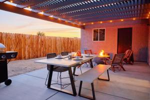 a patio with a table and chairs and a fence at Live Centered with Hot Tub, Fire Pit In Joshua Tree home in Joshua Tree