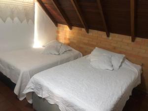 2 camas blancas en una habitación con una pared de ladrillo en Bella casa de campo, con Hidrospa y zonas verdes, en Piedecuesta