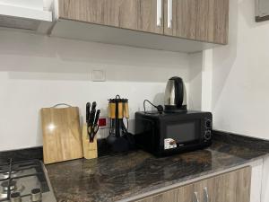a kitchen counter with a microwave and a black microwave oven at Am apartment in Accra