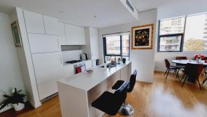 a kitchen with white cabinets and a table with chairs at Pool View of Marquarie Park Paradise in Sydney