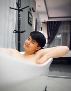 un jeune homme assis dans une baignoire dans l'établissement Casa VESPA at WUA LAI Boutique Hotel Chiang Mai, à Chiang Mai